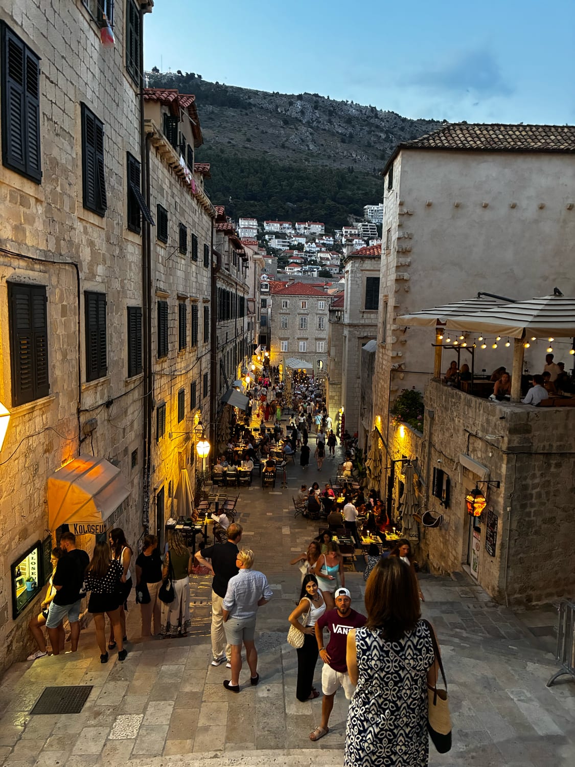 Abendliche Altstadtgasse in Dubrovnik mit Treppe hinunter zum Stradun, Restaurants und Lichterketten