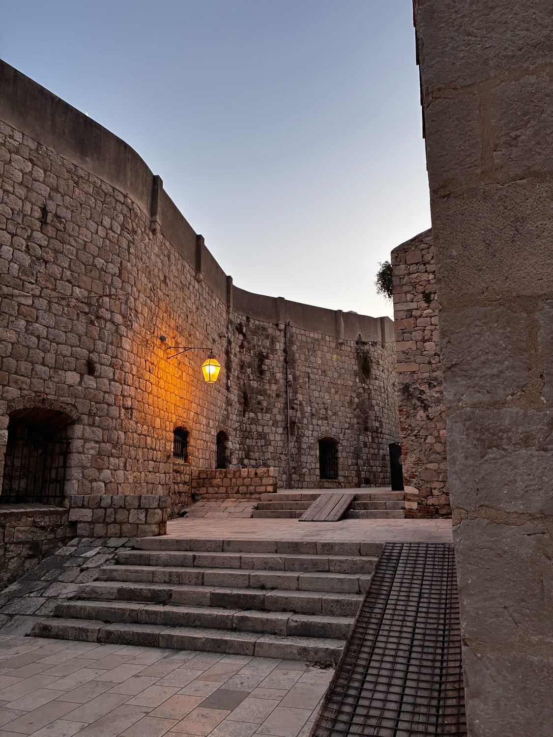 Steinerner Innenhof an der Festungsmauer von Dubrovnik mit leuchtender Laterne in der Abenddämmerung